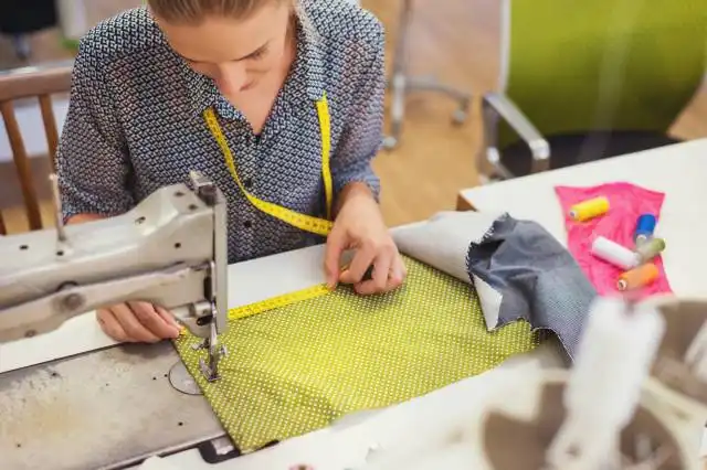 Beautiful young woman sewing clothes with sewing machine.