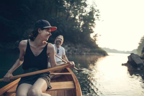 Smiling couple paddling canoe on a lake, copy space.