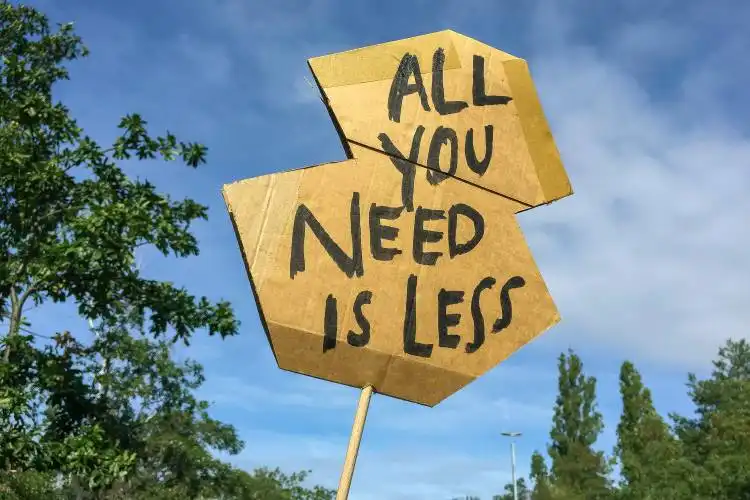a cardboard sign that says all you need is less