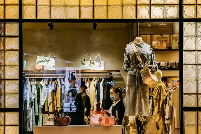 man in beige and brown uniform standing in front of clothes store