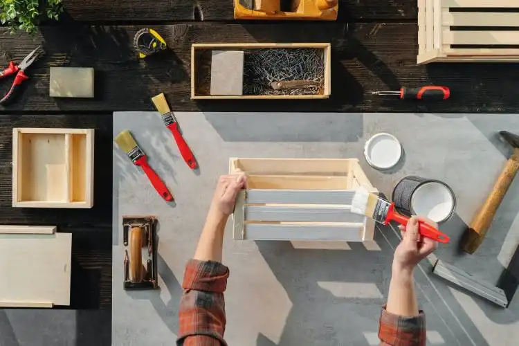 A top view of unrecognizable woman making wooden boxes, small business and desktop concept.