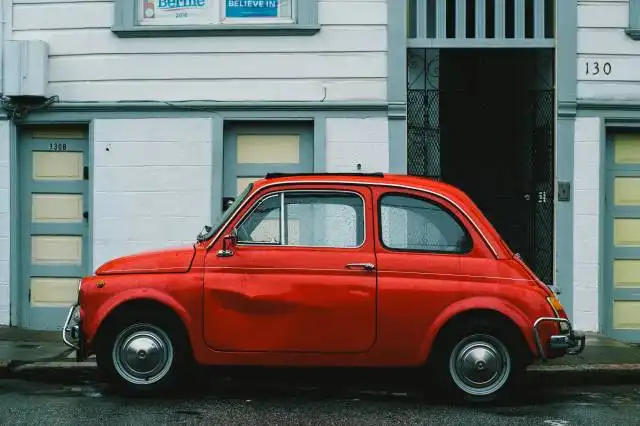 red Volkswagen Beetle car parked in front of white house