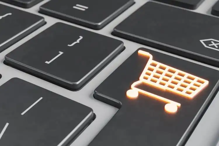 close up of a luminous shopping cart symbol on the enter key of a laptop. e-commerce concept, online business, dropshipping,