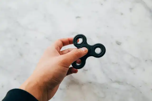 person using black fidget spinner