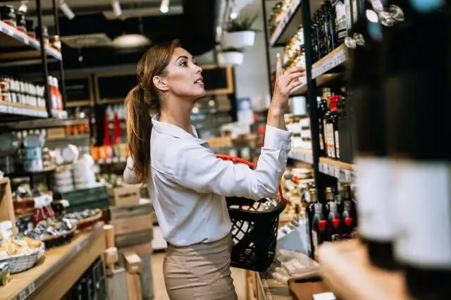 Beautiful young and elegant woman buying some healthy food and drink in modern supermarket or grocery store. Lifestyle and co