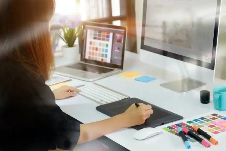 Young asian graphic designer working on computer using digital tablet at office.