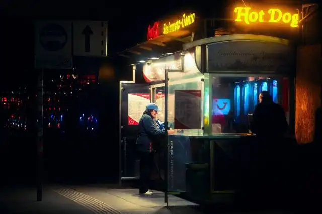 man in black jacket standing near store during night time