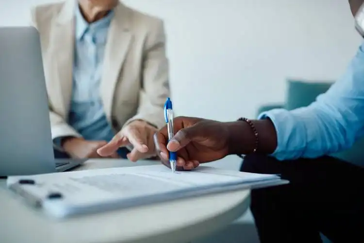 Close-up of financial advisor closing a deal with her client and pointing on a place of signature in the contract.