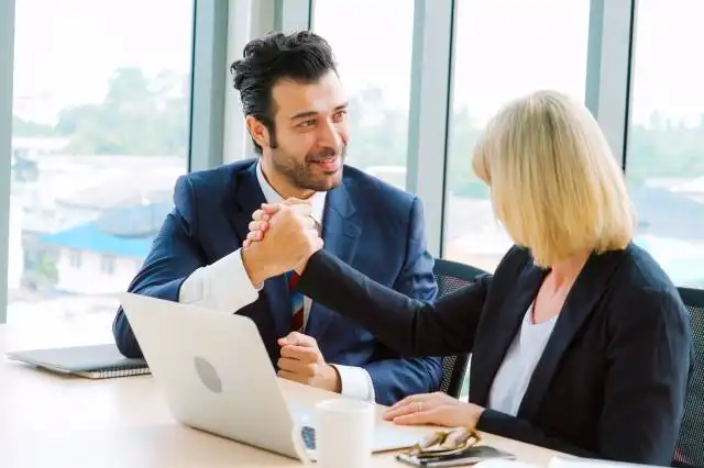 Two happy business people celebrate at office meeting room. Successful businessman congratulate project success with colleagu