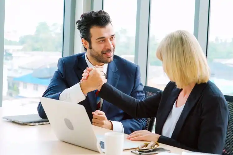 Two happy business people celebrate at office meeting room. Successful businessman congratulate project success with colleagu