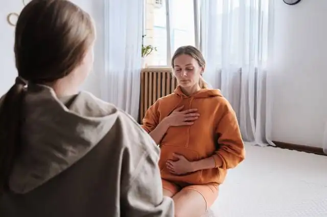 a woman sitting on the floor with her stomach exposed