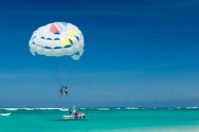 two person riding parachute near beach