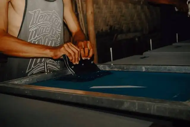 man in white tank top standing beside blue and silver table