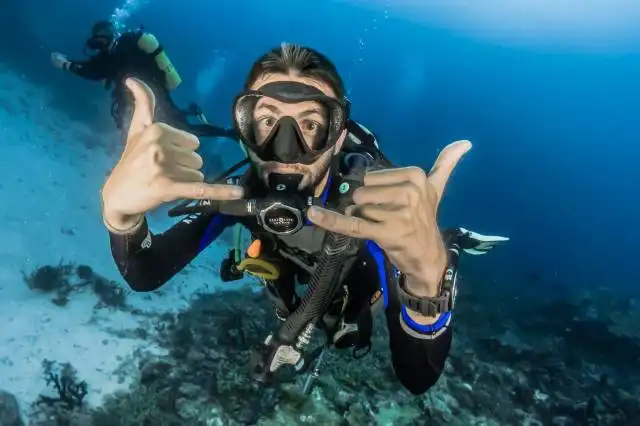 man underwater making hand signs
