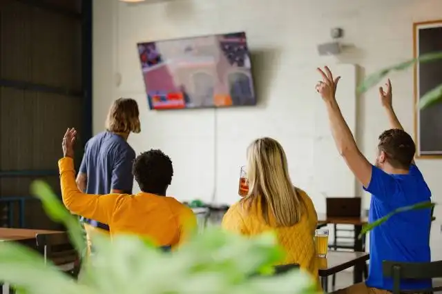 a group of people sitting at a table with their arms in the air