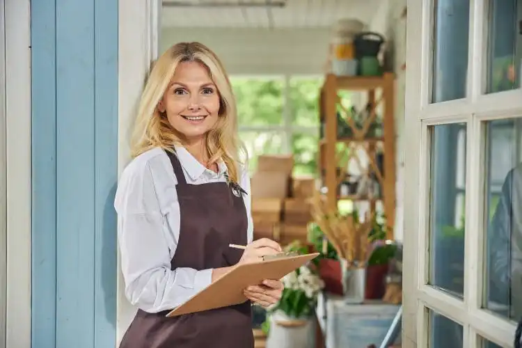 Front view of a smiling lovely middle-aged blonde woman holding a clipboard in her hands