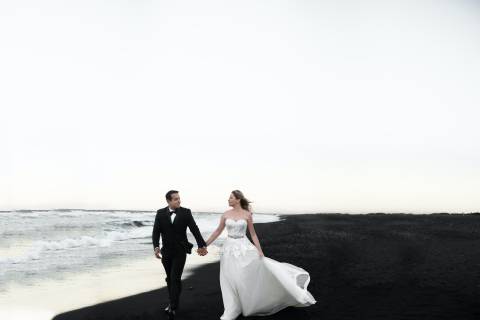 bride and groom walking on beach during daytime