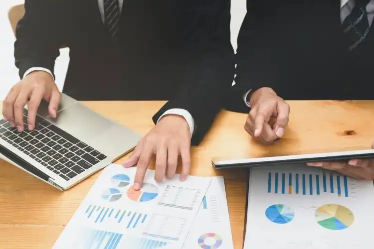 Successful business team consulting the solution with graphs and charts in the meeting room while using laptop