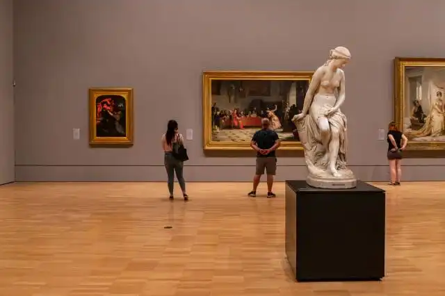 woman in black long sleeve shirt standing near white statue
