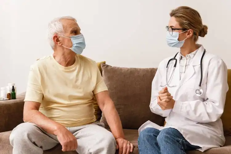 Young woman doctor give a consultation to elderly man during home visit