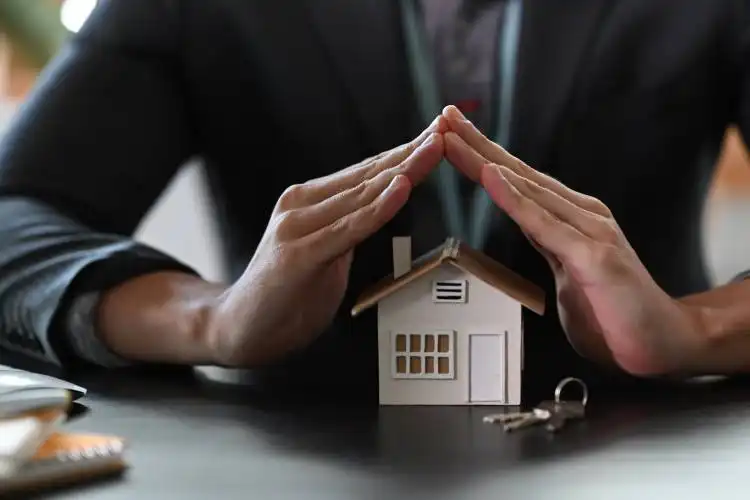 Estate agent hands over house model for protection and care. Property insurance concept.