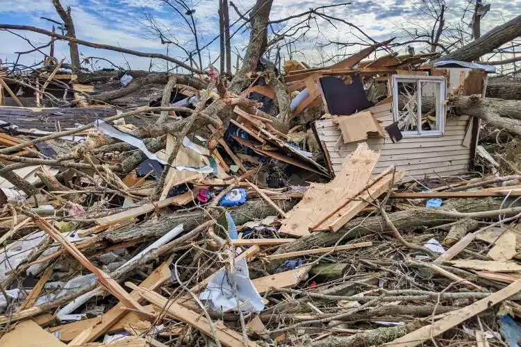 a pile of debris with a house in the background