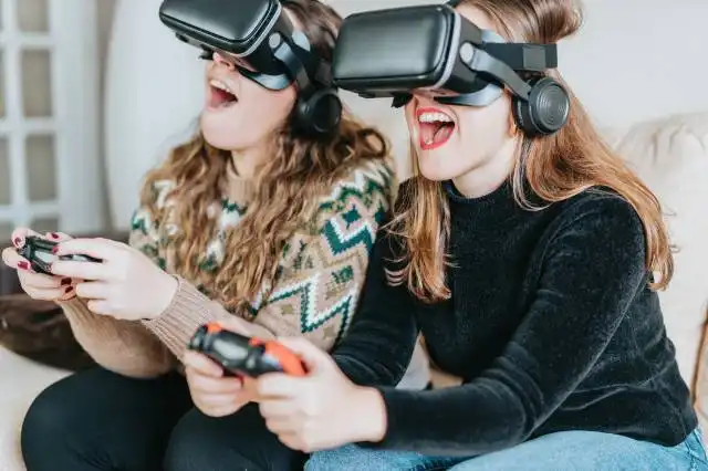 two women sitting on a couch wearing virtual headsets